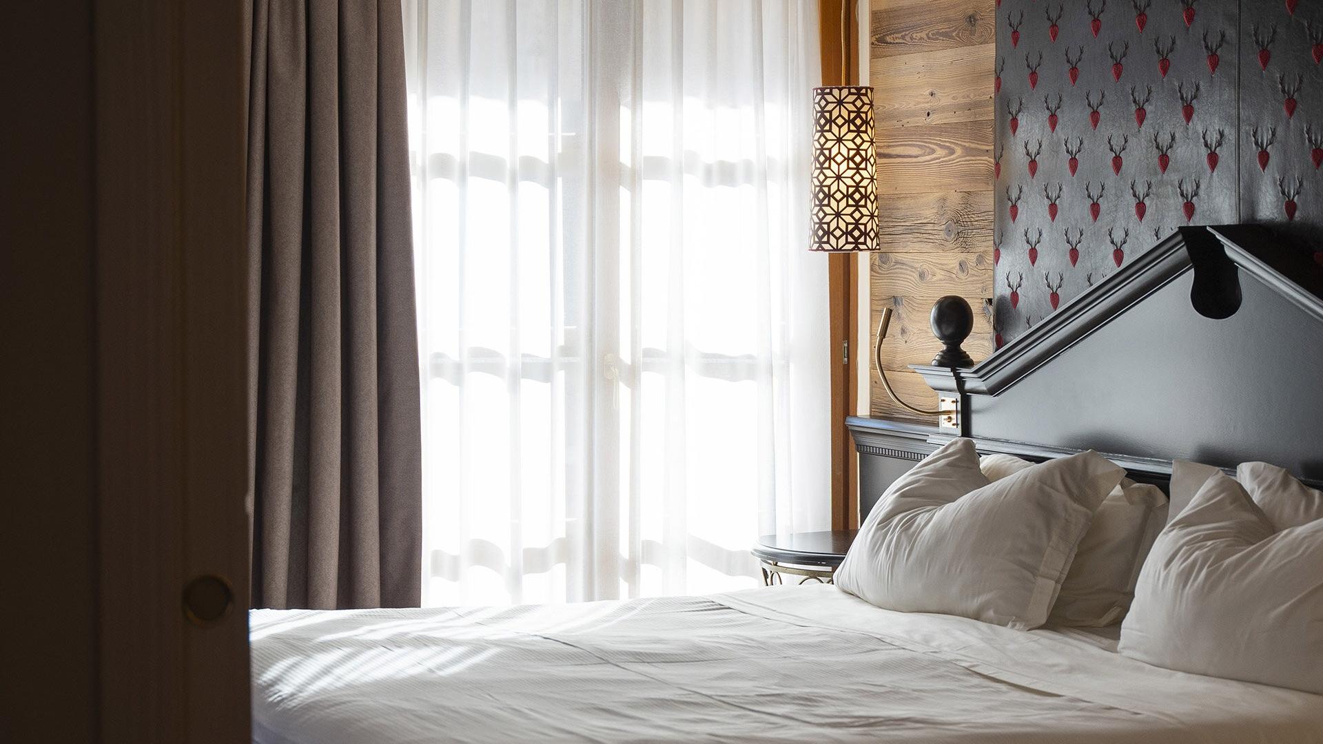 Camera accogliente con letto soffice, luce calda e dettagli in legno rustico.