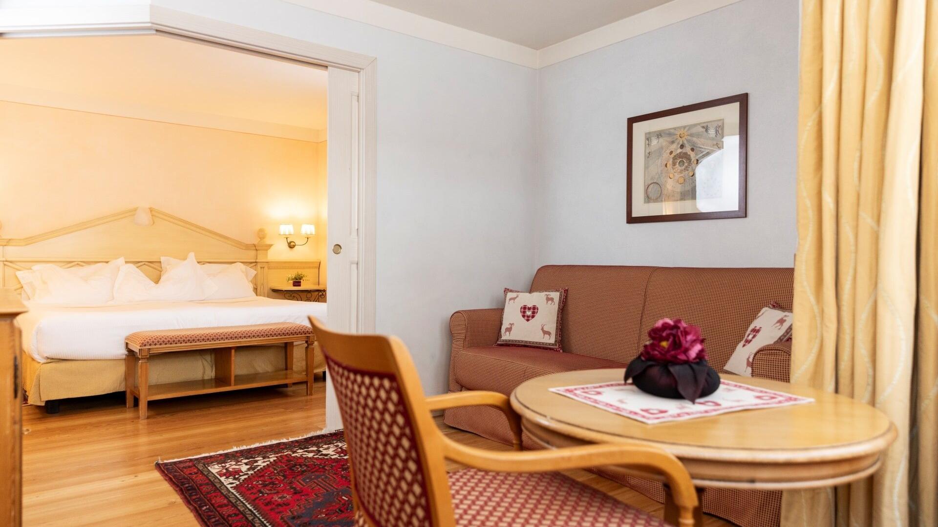 Camera accogliente con letto matrimoniale, divano e tavolino, atmosfera calda e rilassante.