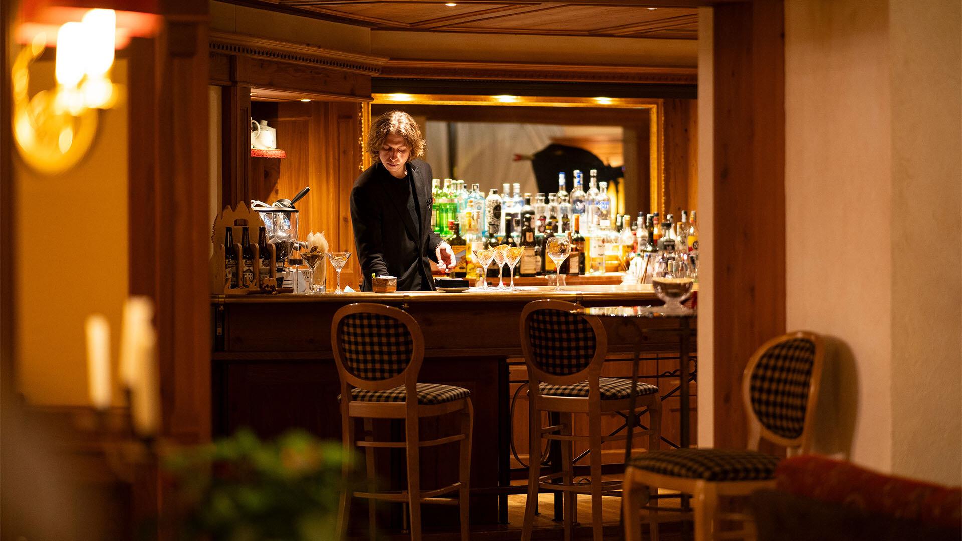 Bar accogliente in legno, luci soffuse, bartender prepara cocktail con eleganza.