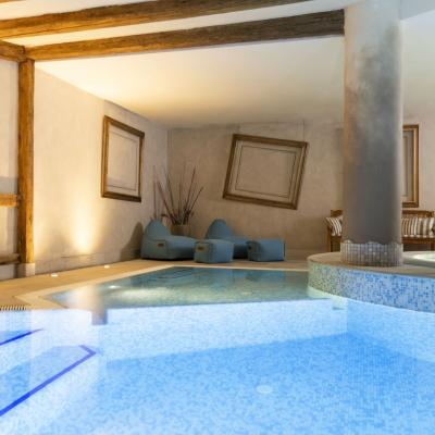 Piscina interna elegante, luci soffuse, arredi accoglienti e atmosfera rilassante.