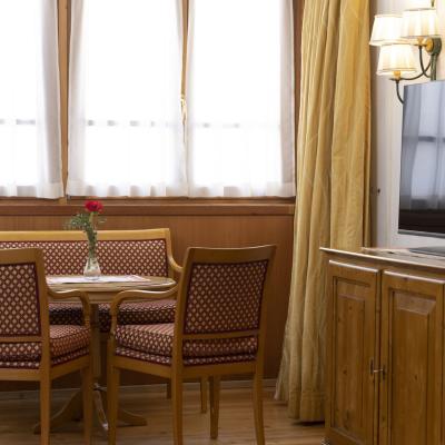 Sala accogliente con tavolo, sedie eleganti, fiore rosso e TV su mobile di legno.