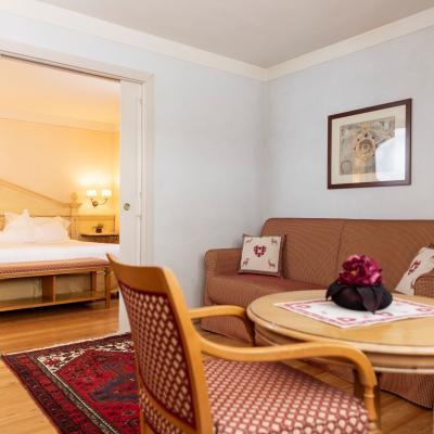 Camera accogliente, letto matrimoniale, divano rosso, arredi caldi, atmosfera intima e rilassante.