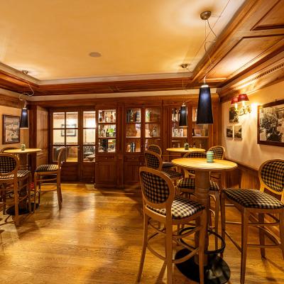 Accogliente bar in legno, luci soffuse, atmosfera calda e intima, sedie eleganti.