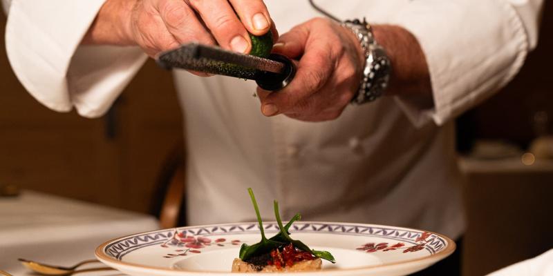 Chef grattugia lime su piatto elegante, creando un'atmosfera di raffinatezza culinaria.