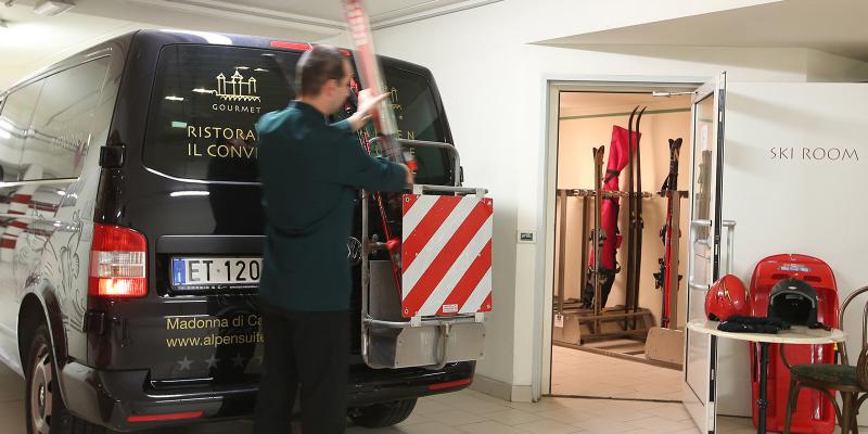 Un uomo carica sci su un furgone vicino a una sala sci accogliente.