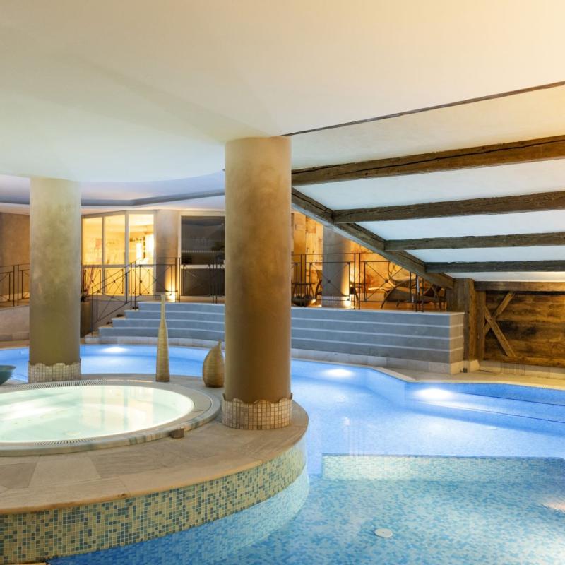 Un'elegante spa con vasche idromassaggio e piscina, atmosfera calda e rilassante.