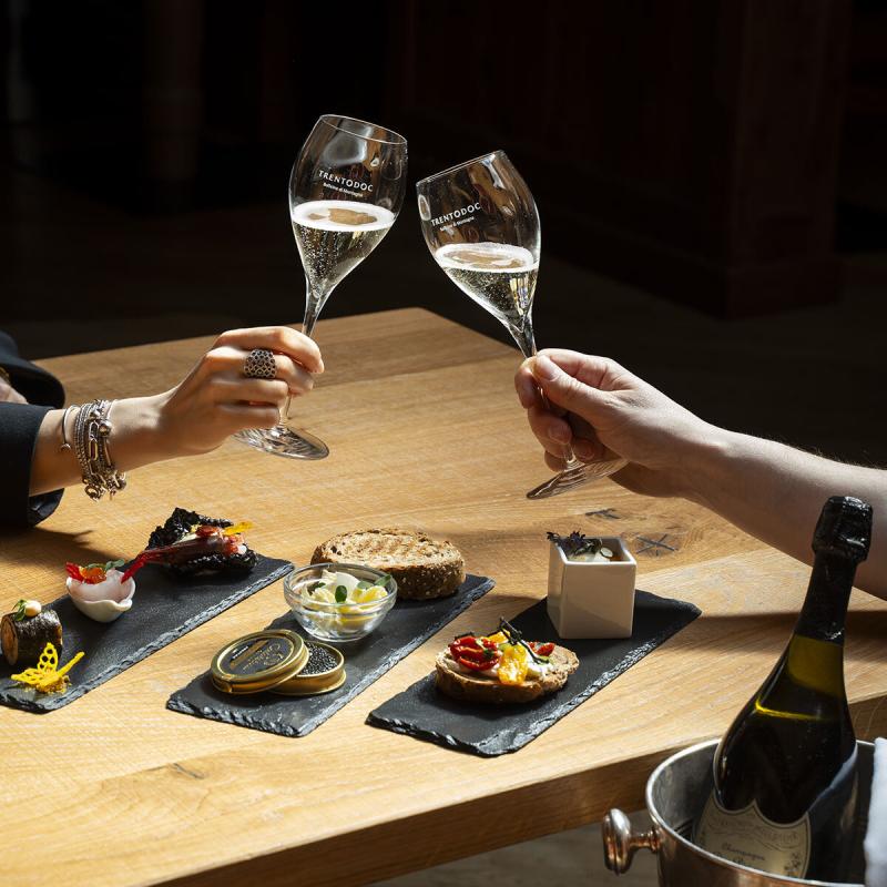 Brindisi elegante con calici di spumante, cibo gourmet su piatti di ardesia.