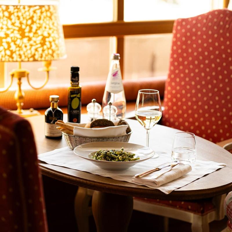 Tavola elegante con pasta, vino bianco, lampada calda e atmosfera accogliente.