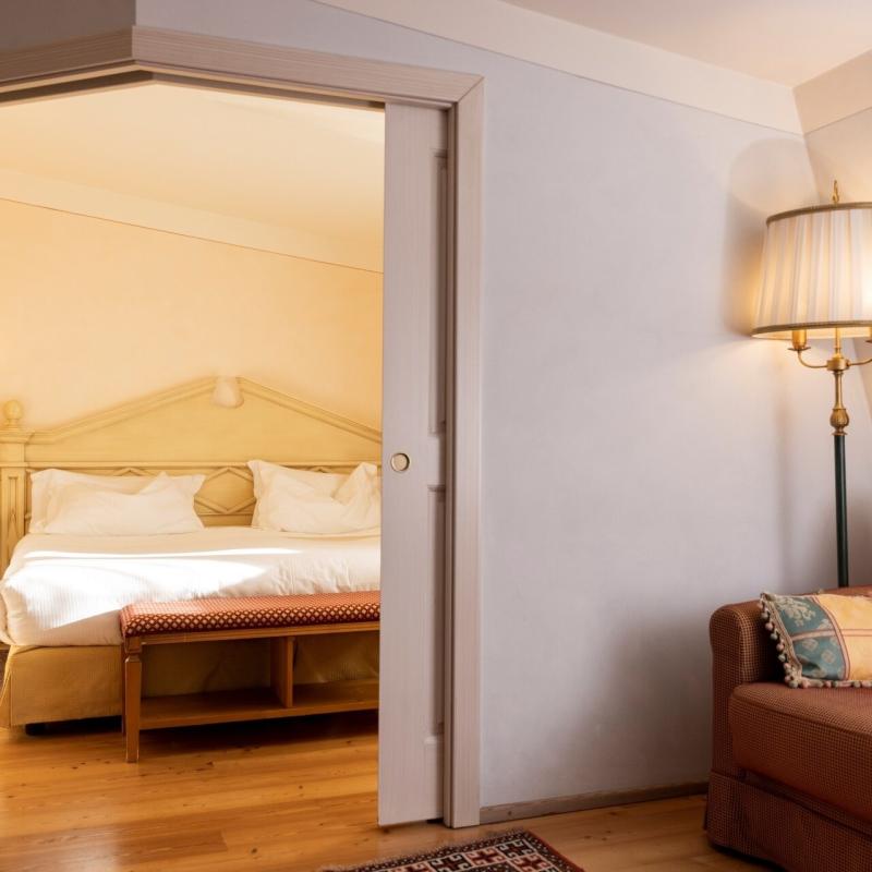 Camera accogliente con letto elegante, divano comodo e lampada calda, atmosfera rilassante e serena.