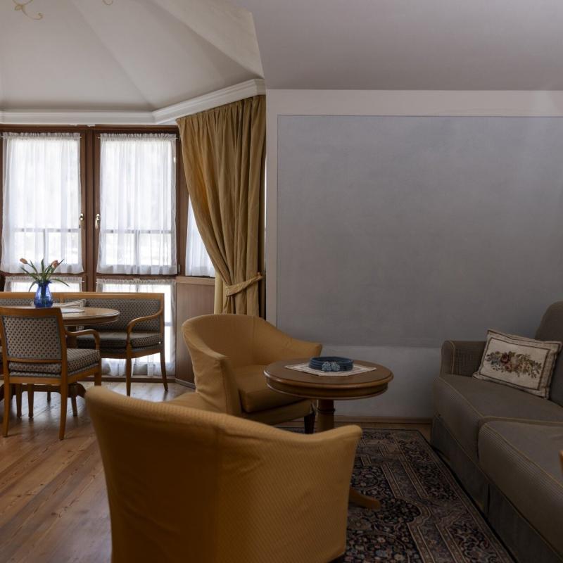 Elegante soggiorno con tavolo, sedie, divano e luce soffusa da ampie finestre.