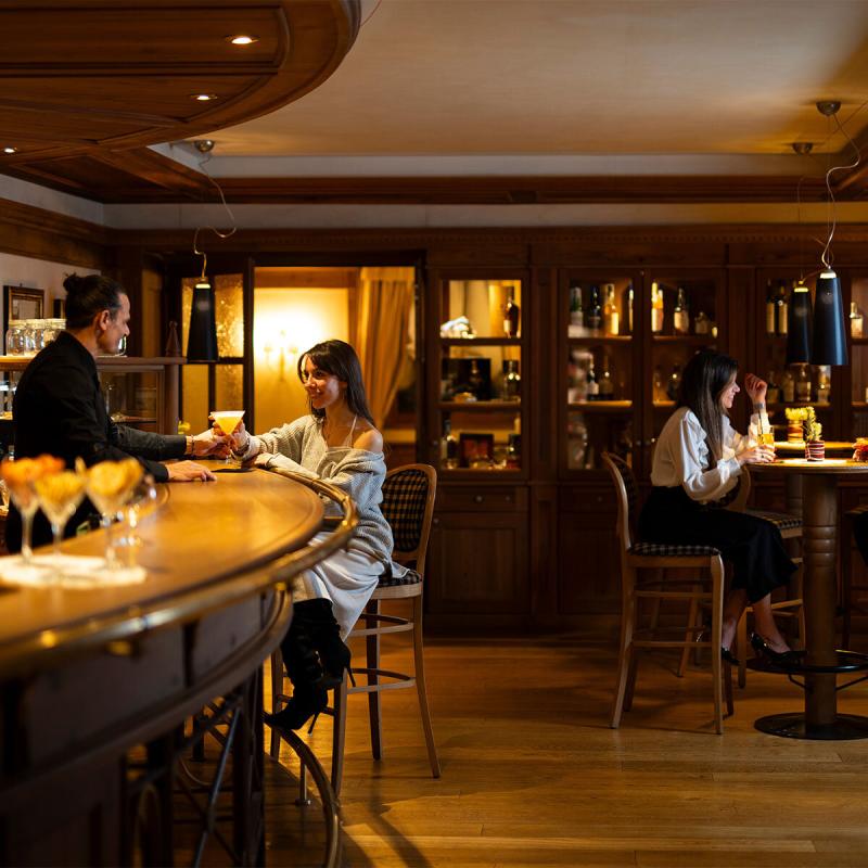 Atmosfera calda in un bar elegante, persone sorridenti e conversazioni piacevoli.
