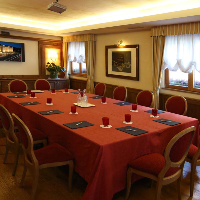 Sala riunioni elegante con tavolo rosso, sedie raffinate e atmosfera accogliente.