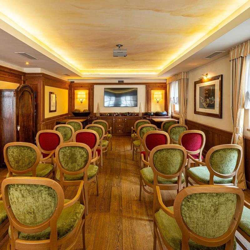 Sala elegante con sedie colorate, atmosfera calda e accogliente, ideale per conferenze intime.